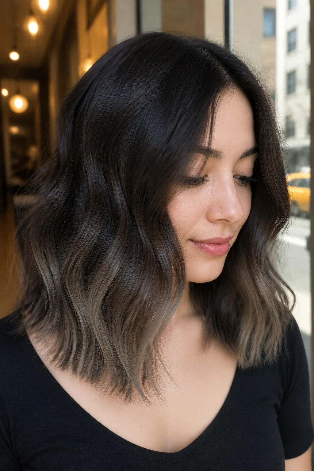 Close-up of a real woman with ash-dusted ends on a wavy brunette lob.