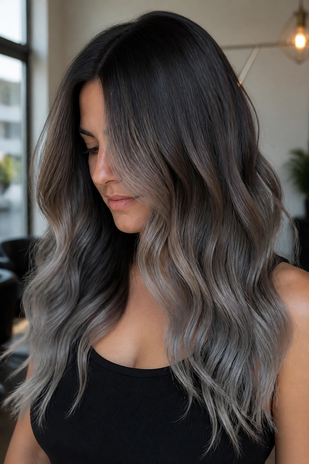 Close-up of a real woman's long hair showing brown-to-gray melt with a deep shadow root in ash gray balayage.