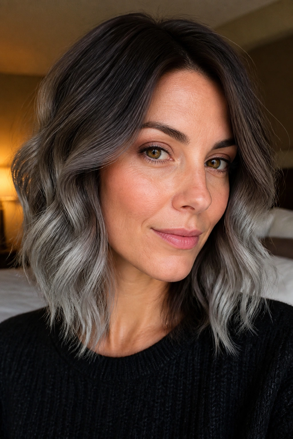Portrait of a woman with ash gray frosted ends on a deep mocha base, shoulder-length wavy hair