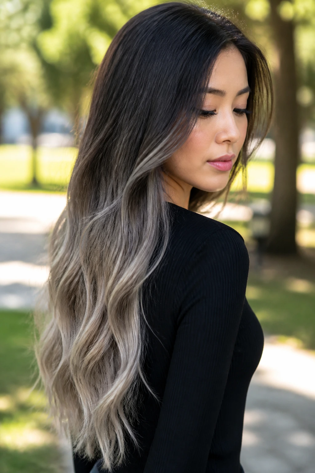 Portrait of a real woman with an ash ombre from dark roots to ash blonde ends in daylight.