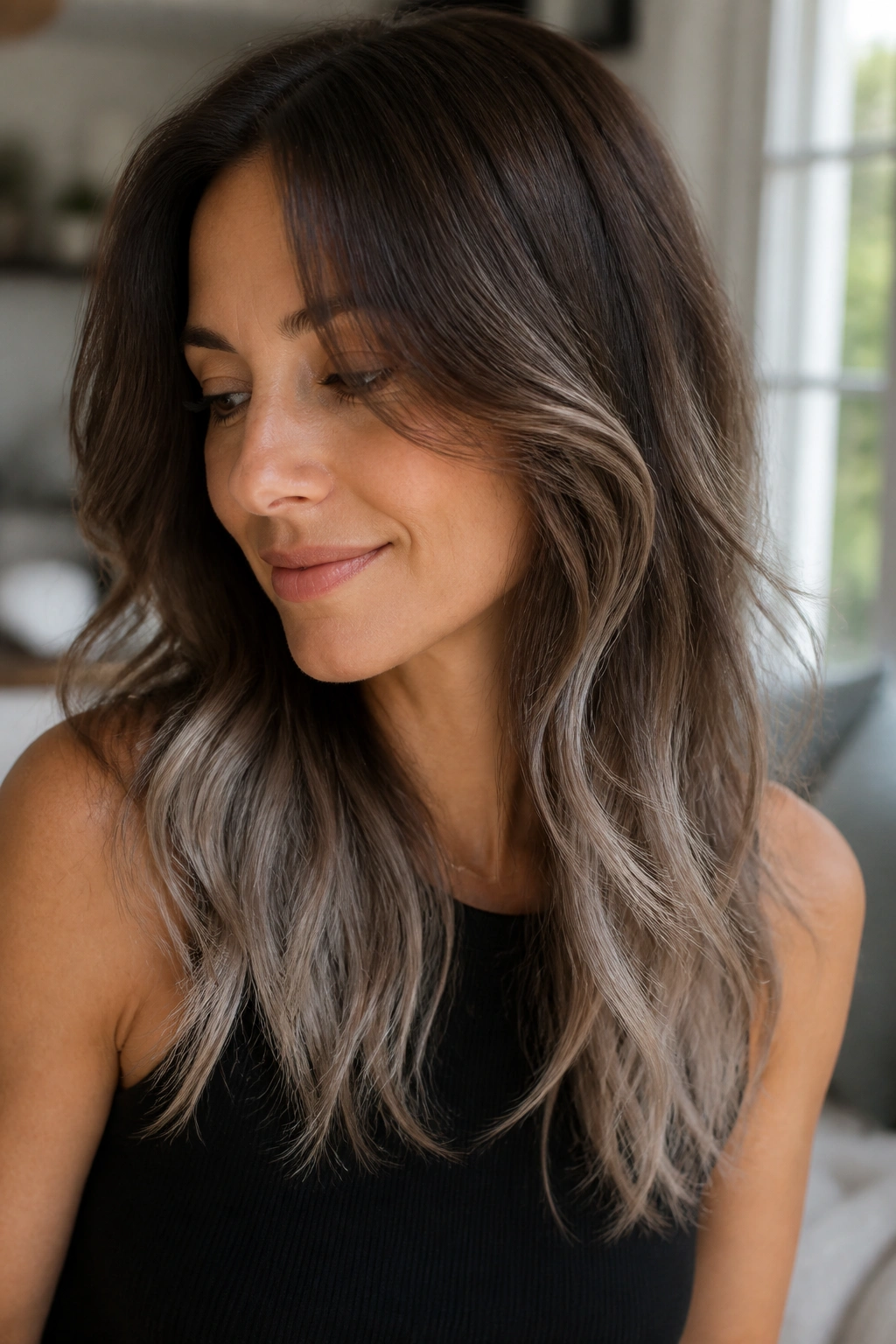 Close-up of a real woman with feathered pepper ends on layered brown hair, smoky silver tips