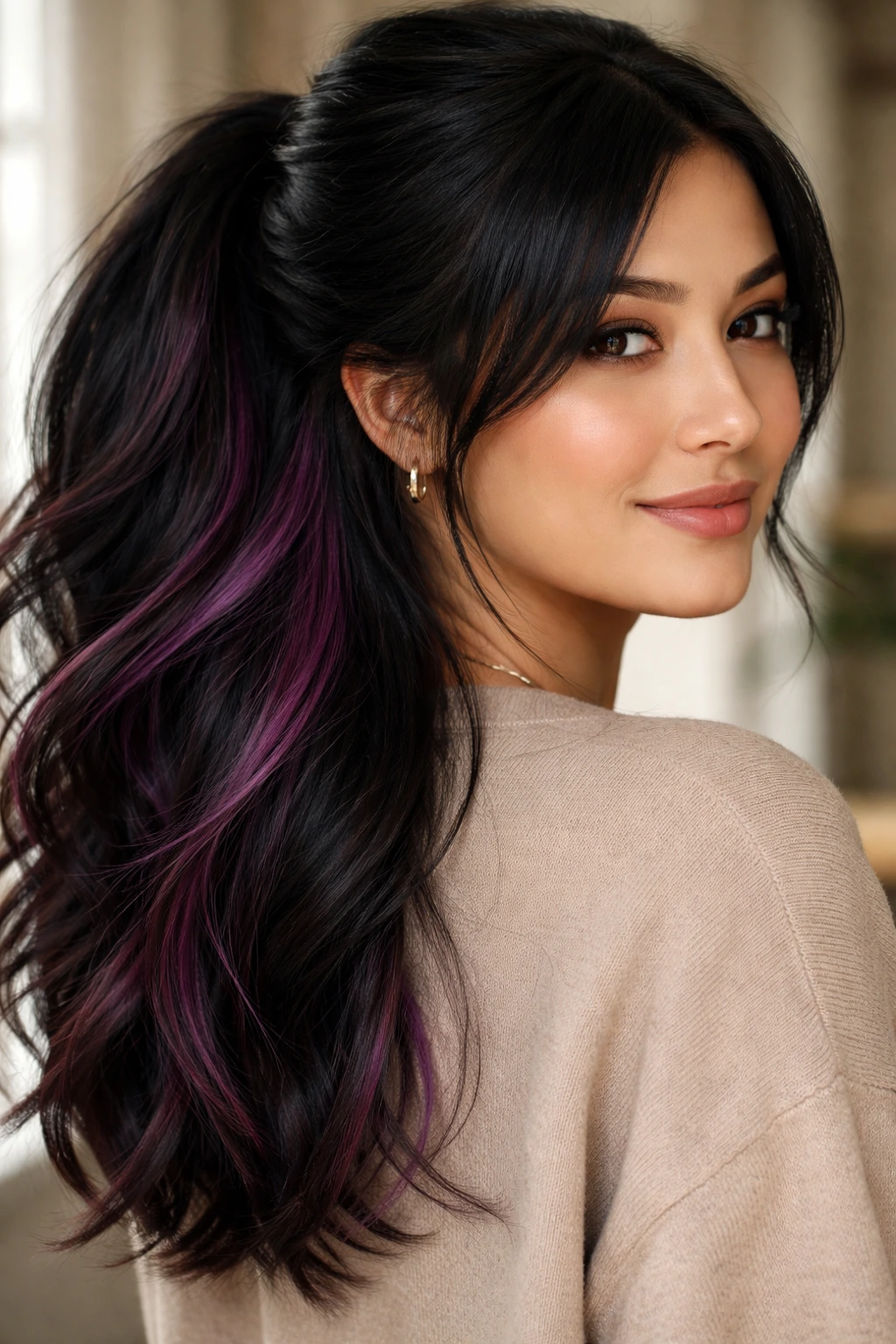 Portrait of a real woman showing berry-purple peekaboo highlights beneath black hair