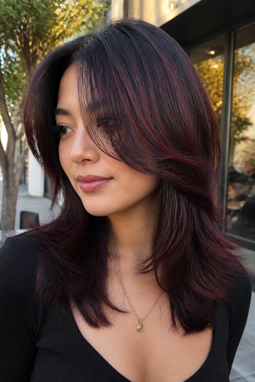 Woman with shoulder-length layered hair in black cherry glaze.
