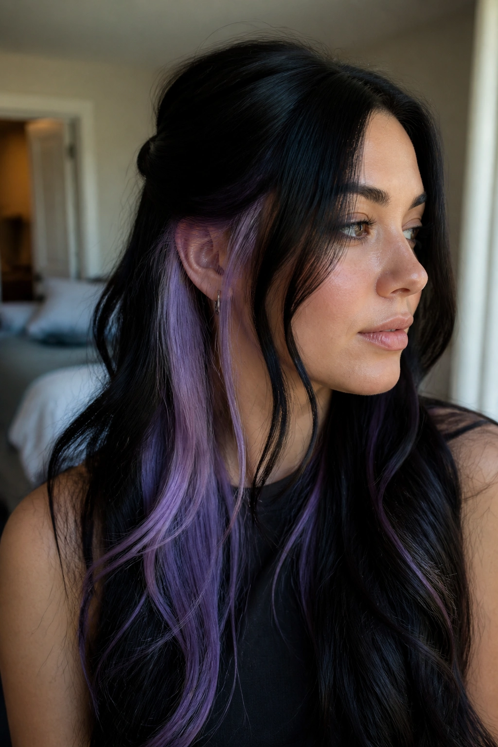 Close-up of black hair with lavender underlayers peeking behind the ear on a real person