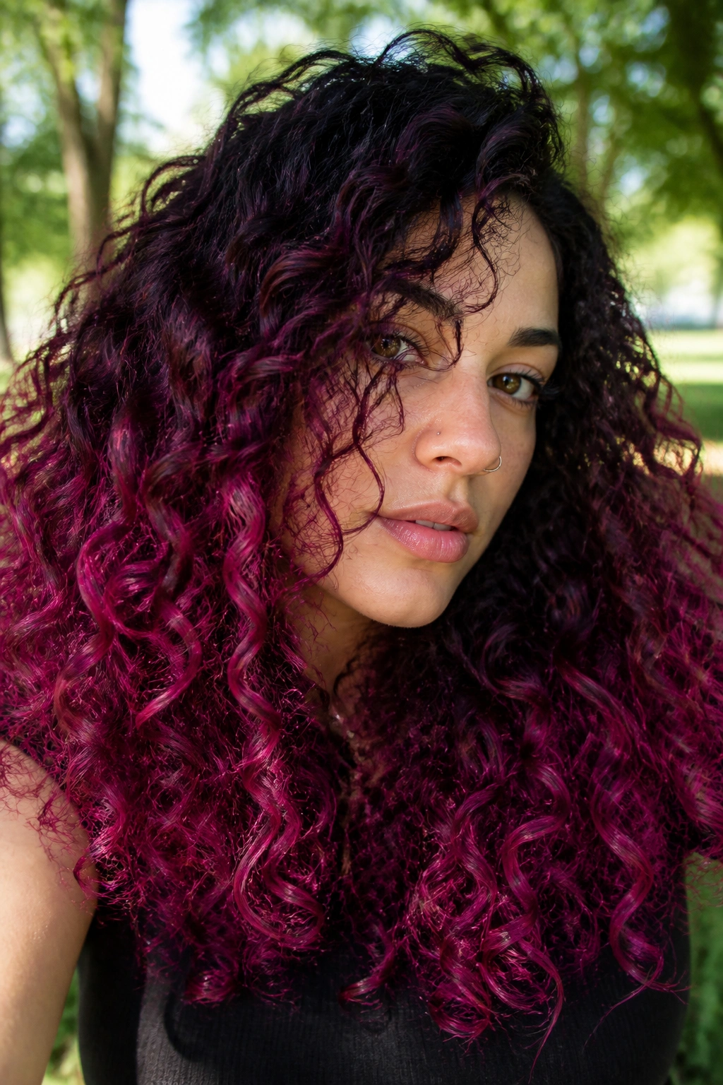 Close-up of a real woman with blackberry to fuchsia melt on curly long hair