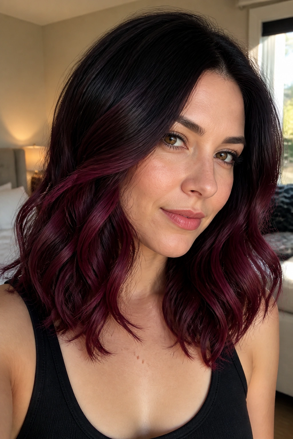 Close-up portrait of a real woman with Blackberry Melt hair, shoulder-length waves fading from near-black roots to blackberry red-violet.