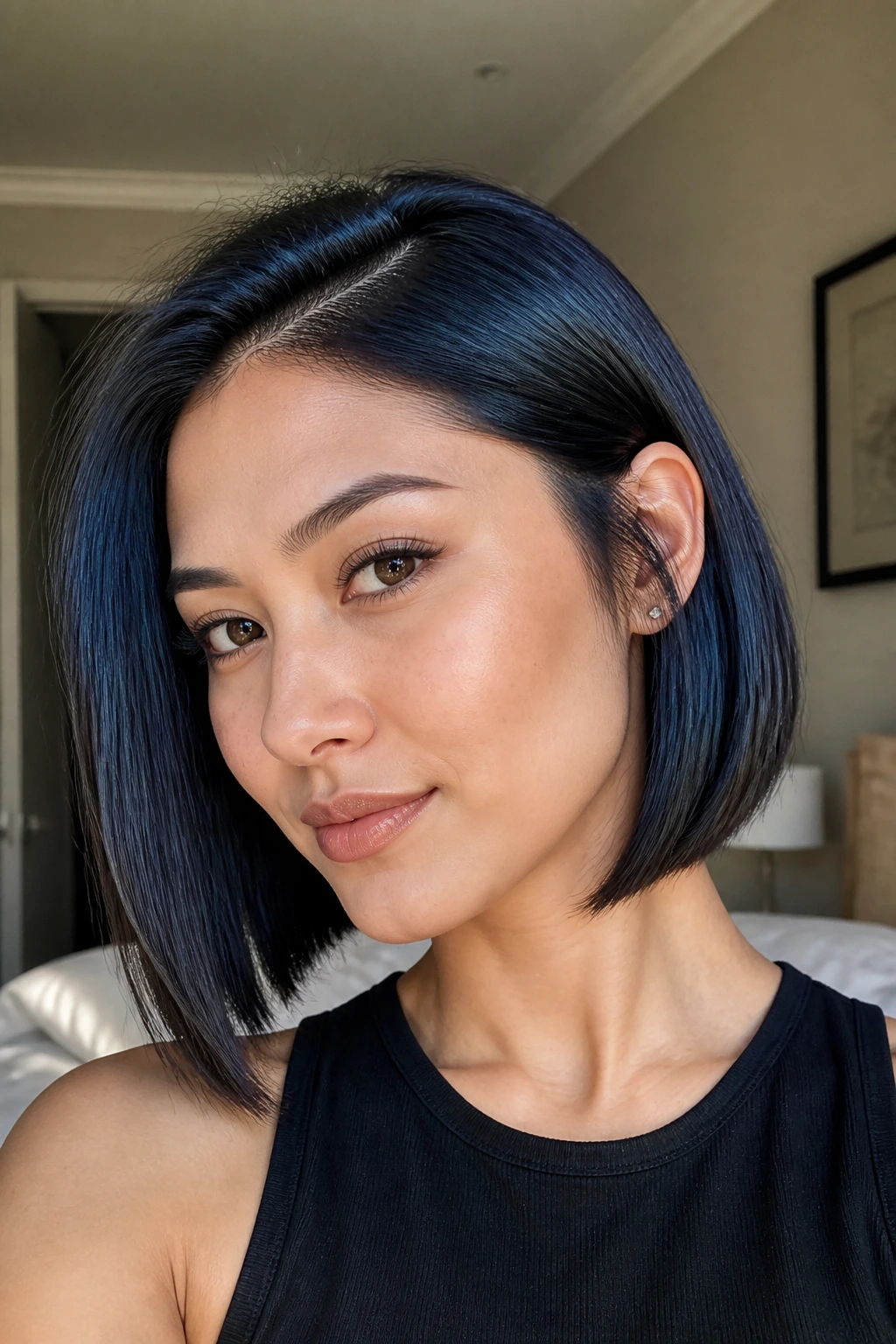 Close-up portrait of a real woman with a jaw-skimming A-line bob in blue-black hair, lit by natural window light.