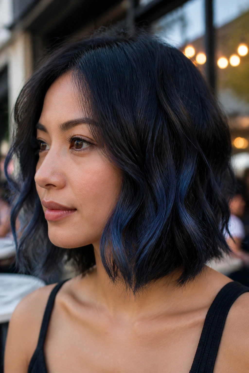 Portrait of a woman with a wavy bob featuring blue-black dimension and lighter ribbons in the lower half.