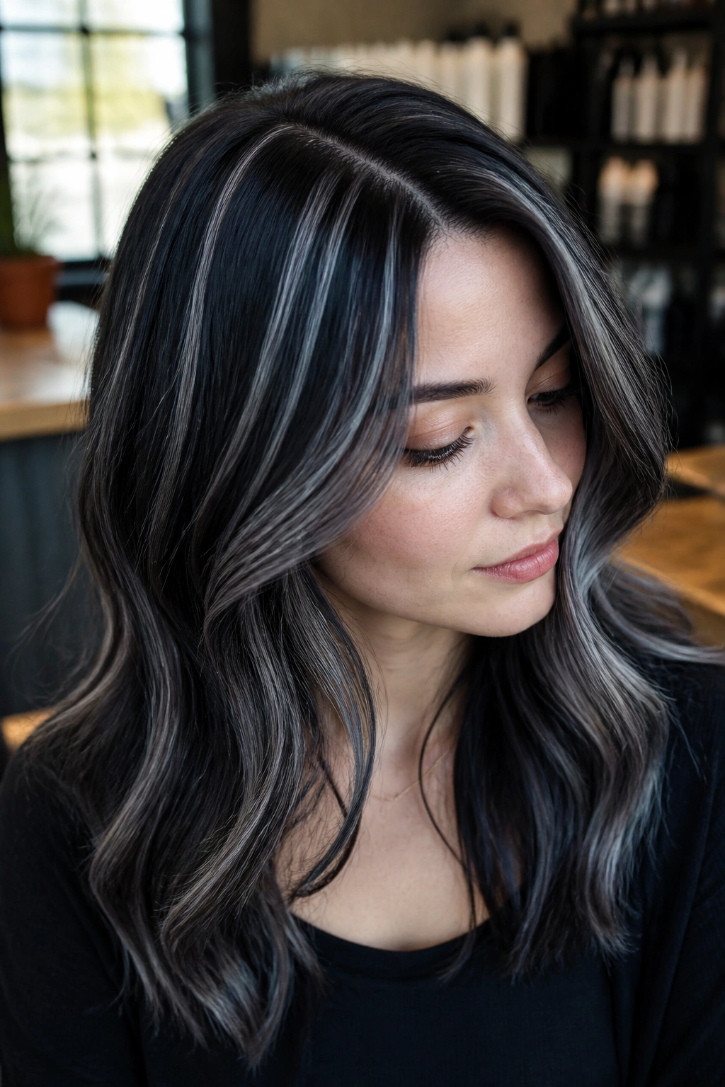 Close-up portrait of a real person with blue-black hair and silver ribbons catching light