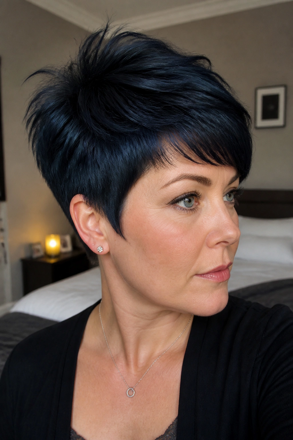 Close-up portrait of a woman with a tapered blue-black pixie showing crown lift