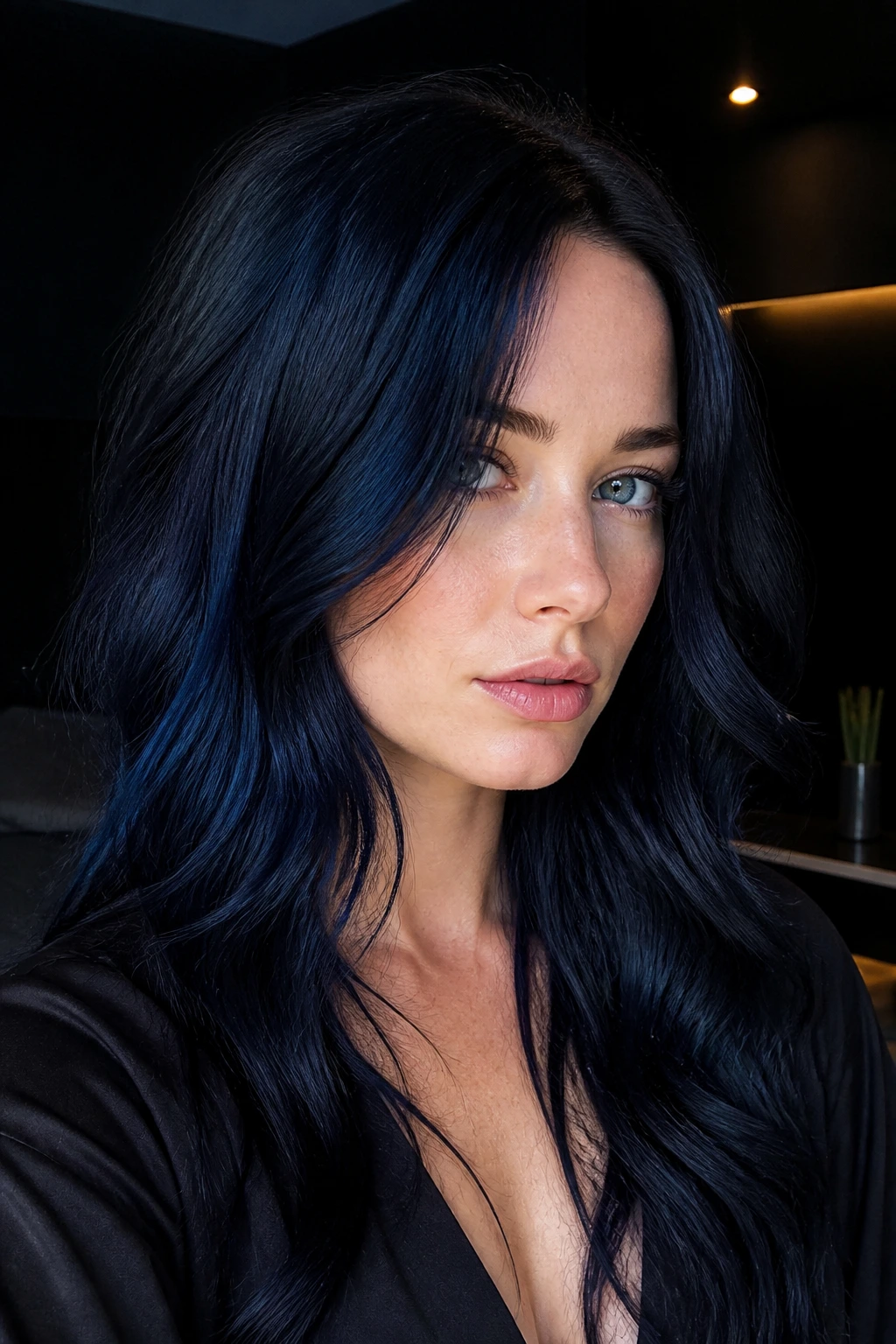 Close-up portrait of a real person with blue-black hair in a modern dimly lit interior