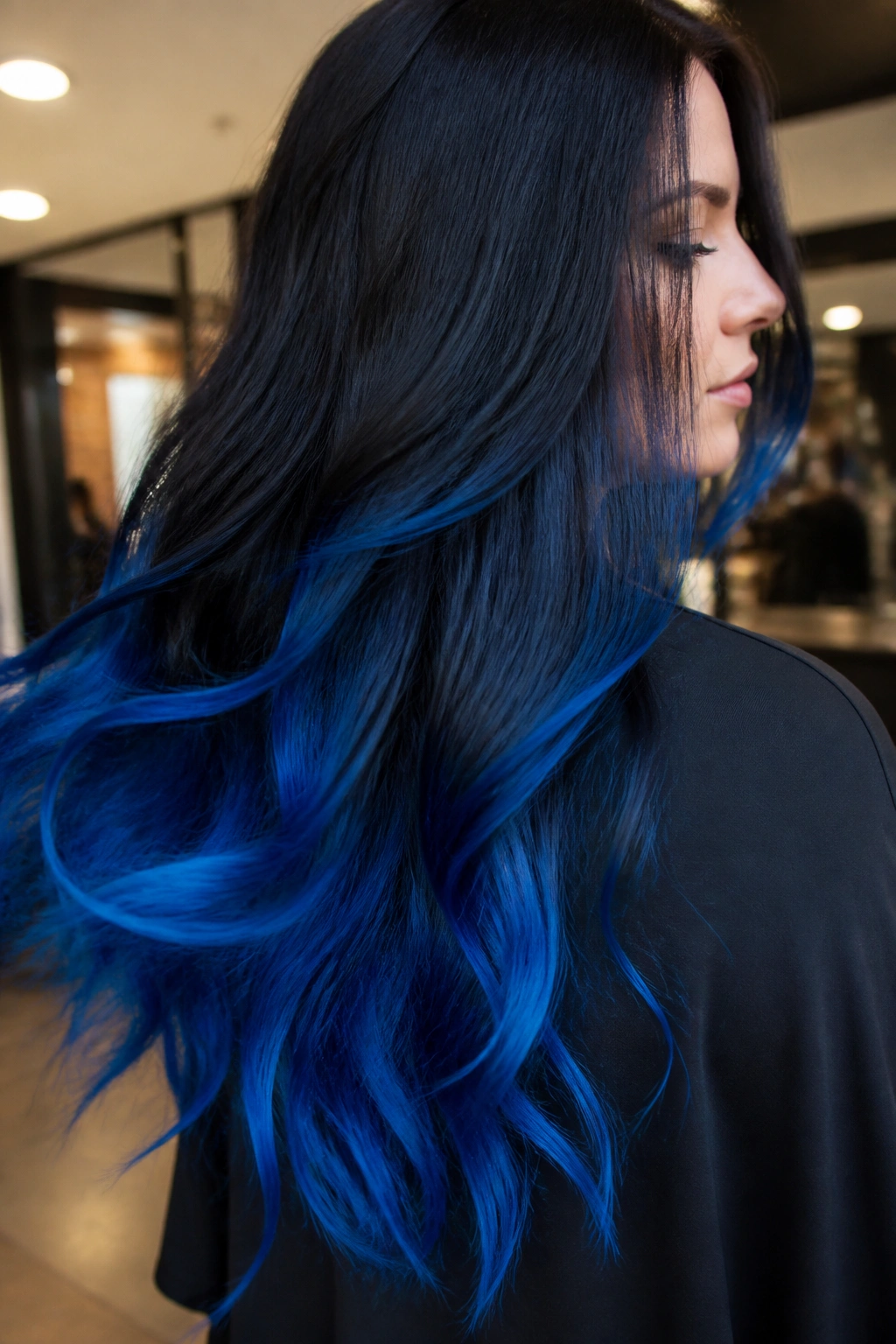 Close-up of a real woman with blue flame ends on long dark-to-blue ombre hair