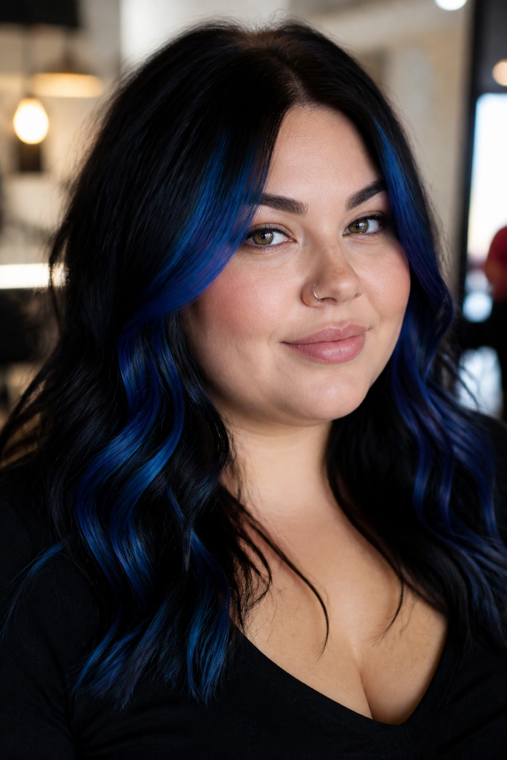 Close-up of a real woman's hair with a shadow root and cobalt blue highlights framing a round face.