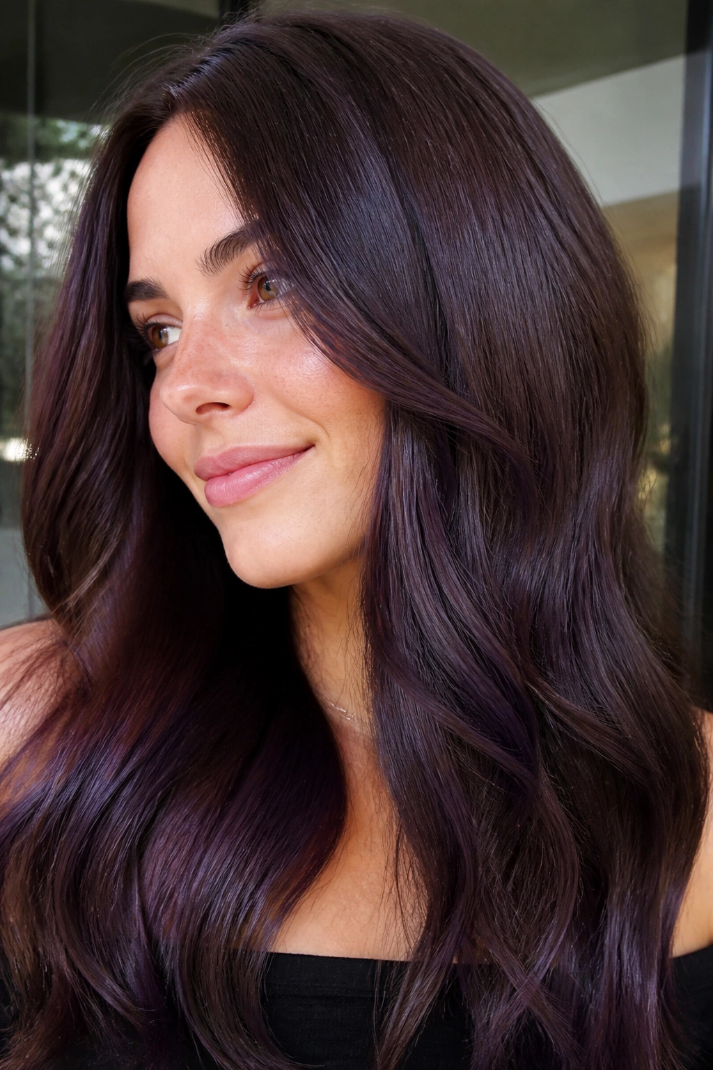 Close-up portrait of a real woman with blue-violet gloss on chestnut brown hair.