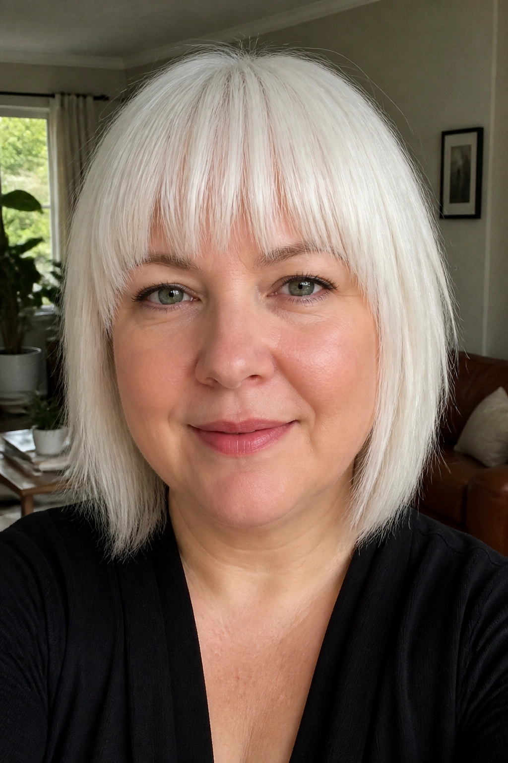 Close-up portrait of a person with high, crisp blunt white bangs above the brows.