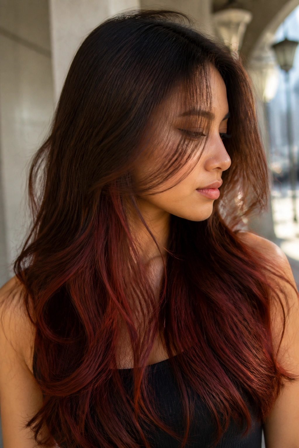 Close-up of a real woman with brick red balayage under brown, peeking through when hair moves.