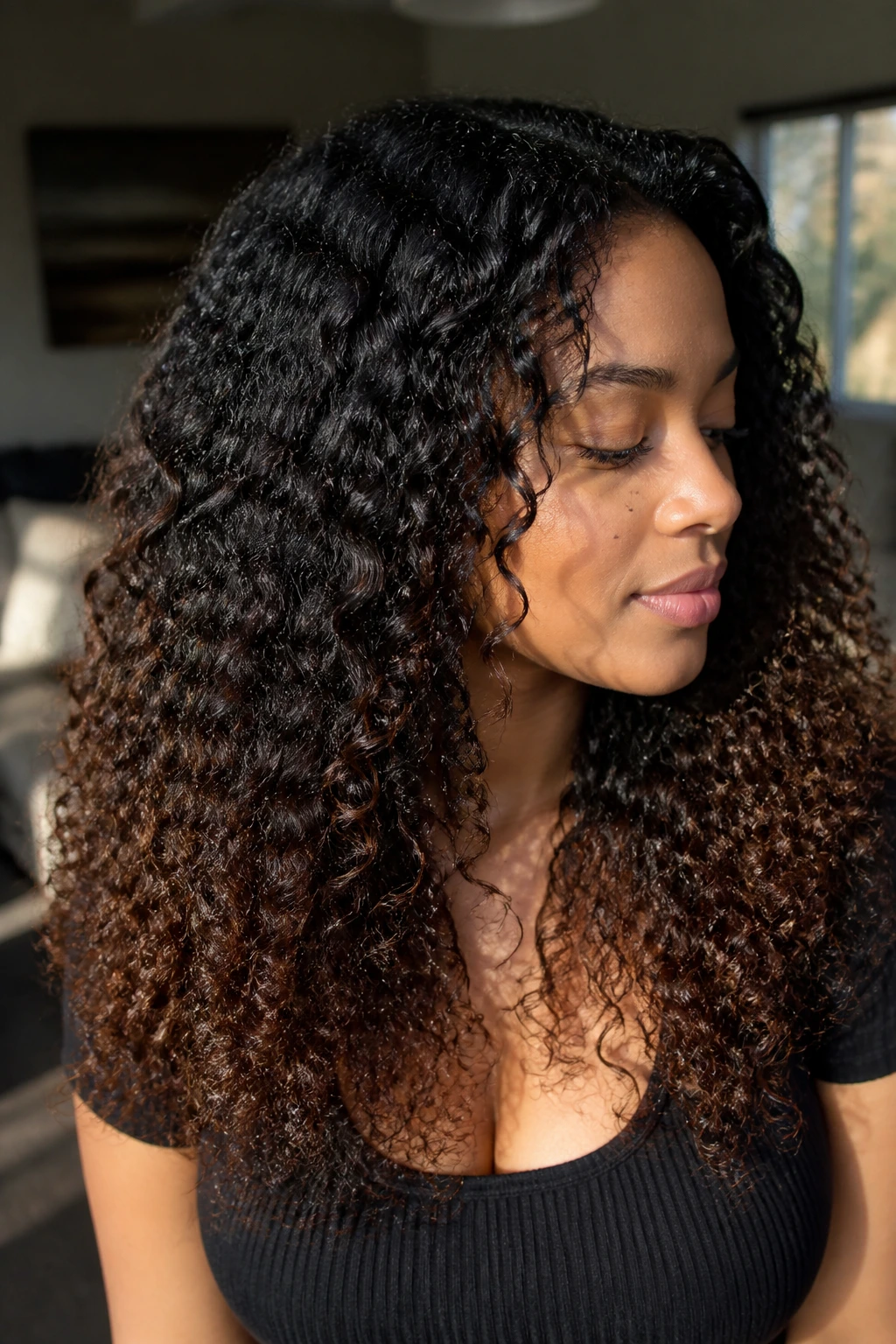 Close-up portrait of a real person with a root-to-end brown-black melt on curls.