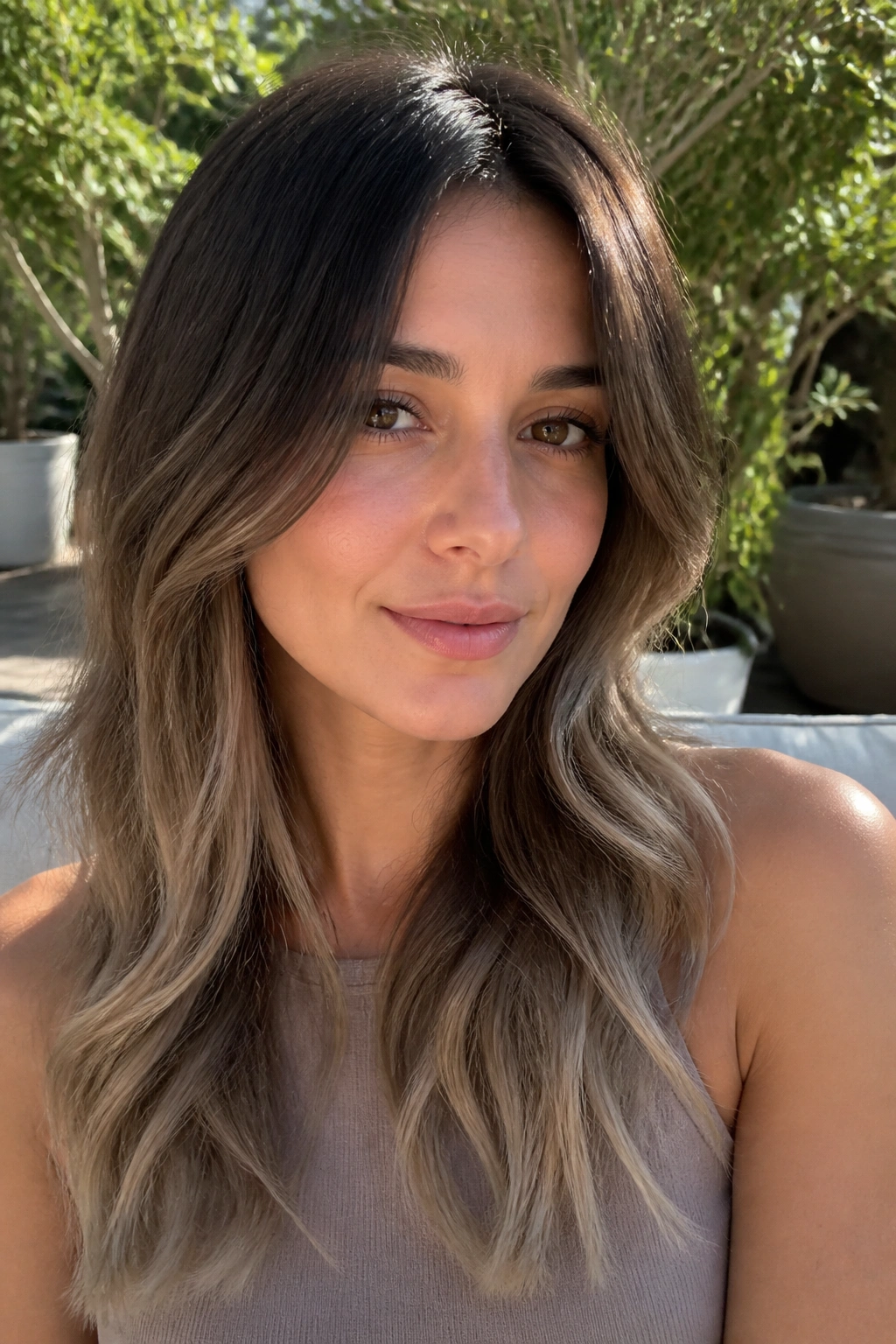 Portrait of a woman with a brunette melt gradient from roots to ash ends.