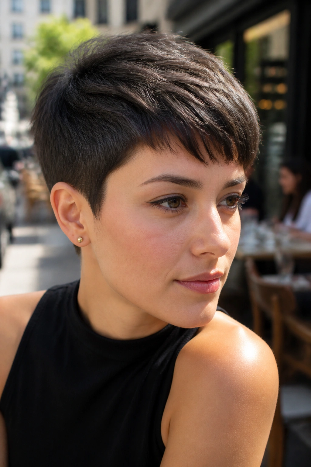 Close-up portrait of a real person with brushed-forward pixie crop, hair sweeping toward the forehead.
