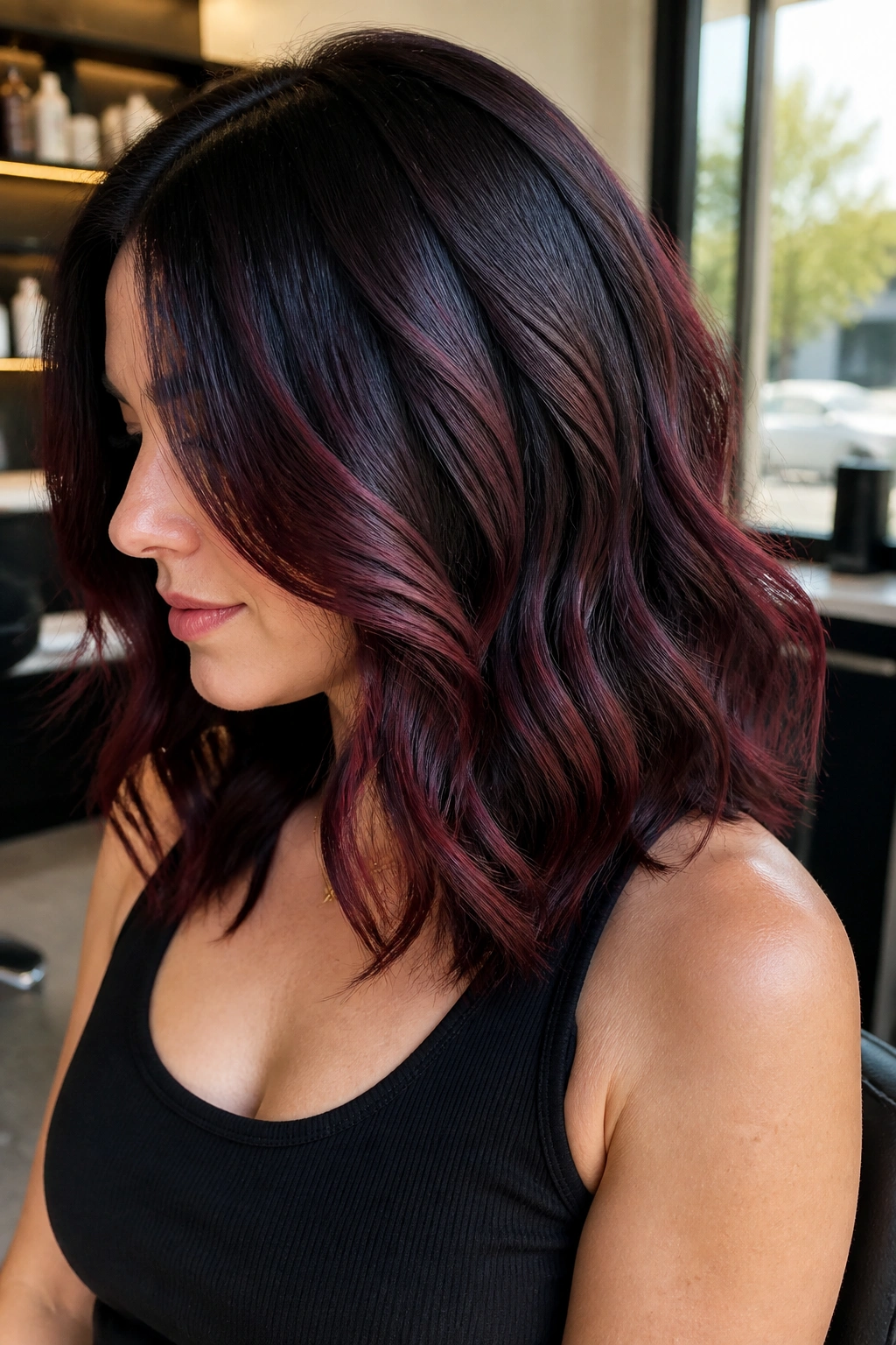 Close-up portrait of a real person with burgundy balayage through a black base