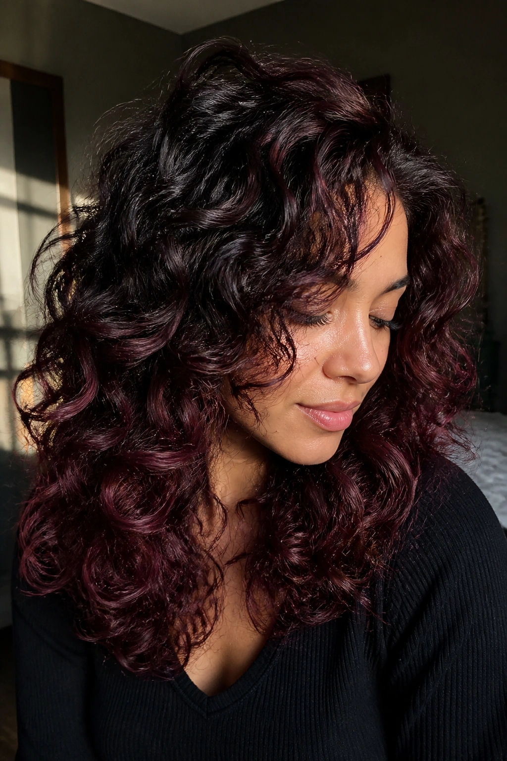 Close-up of real woman with burgundy wine ombre on curly layered hair