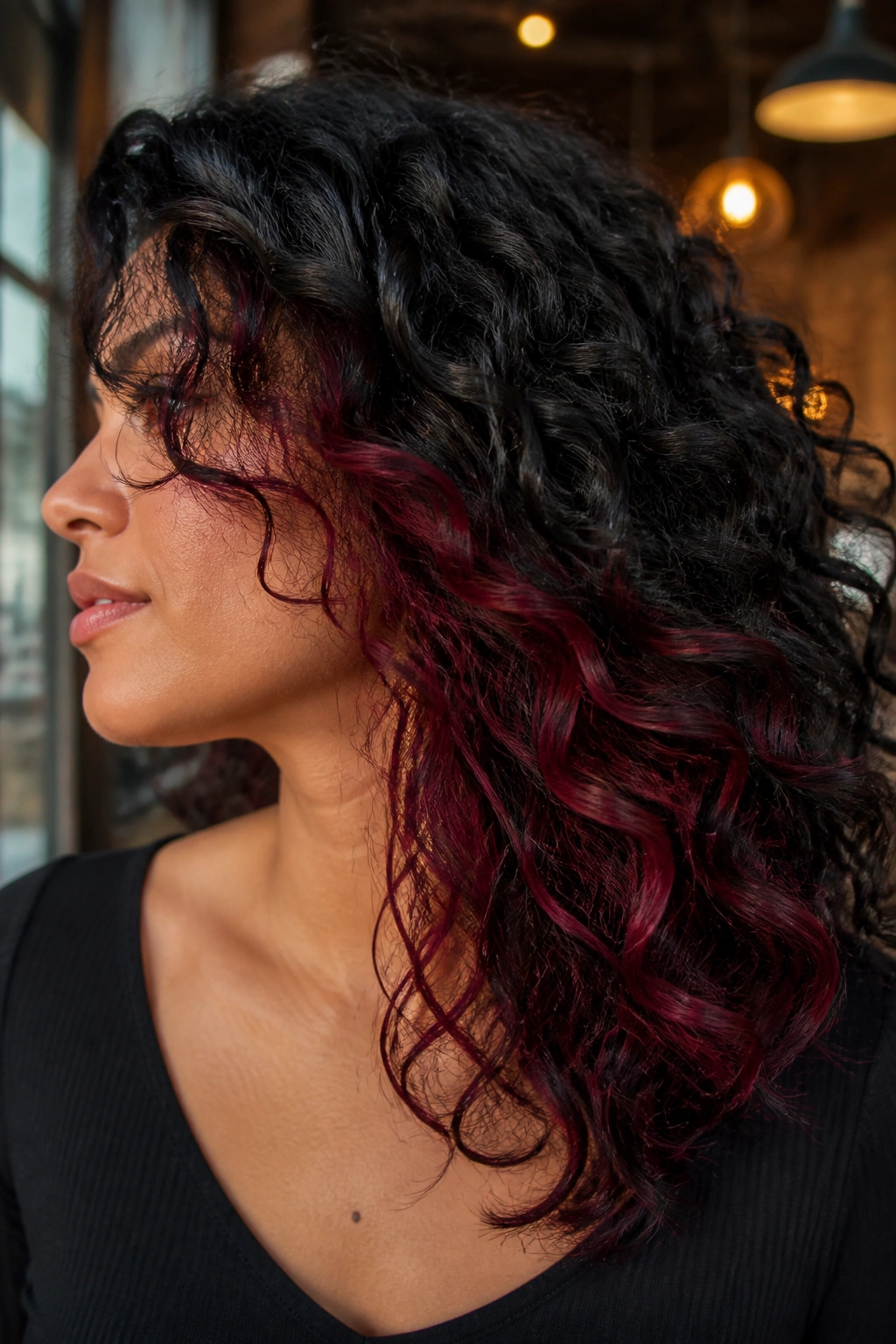 Real person with burgundy peekaboo panels under black curls in a side-profile portrait