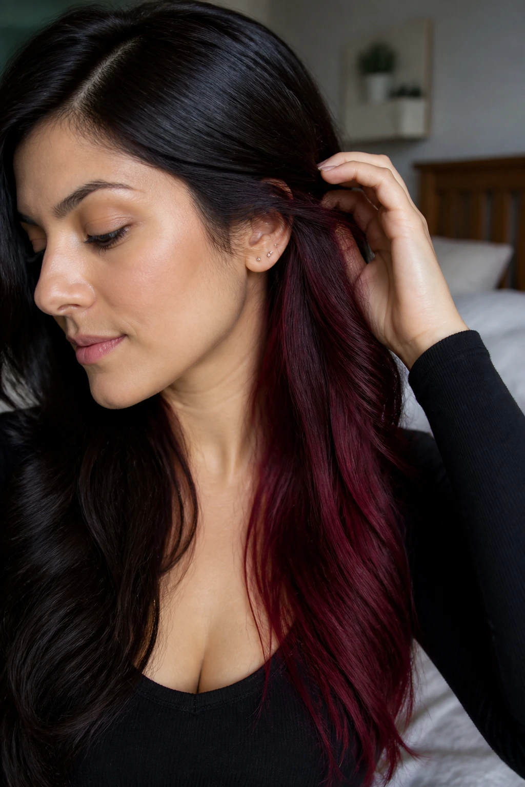 Close-up portrait of a real woman showing burgundy peekaboo ends with a dark top layer.