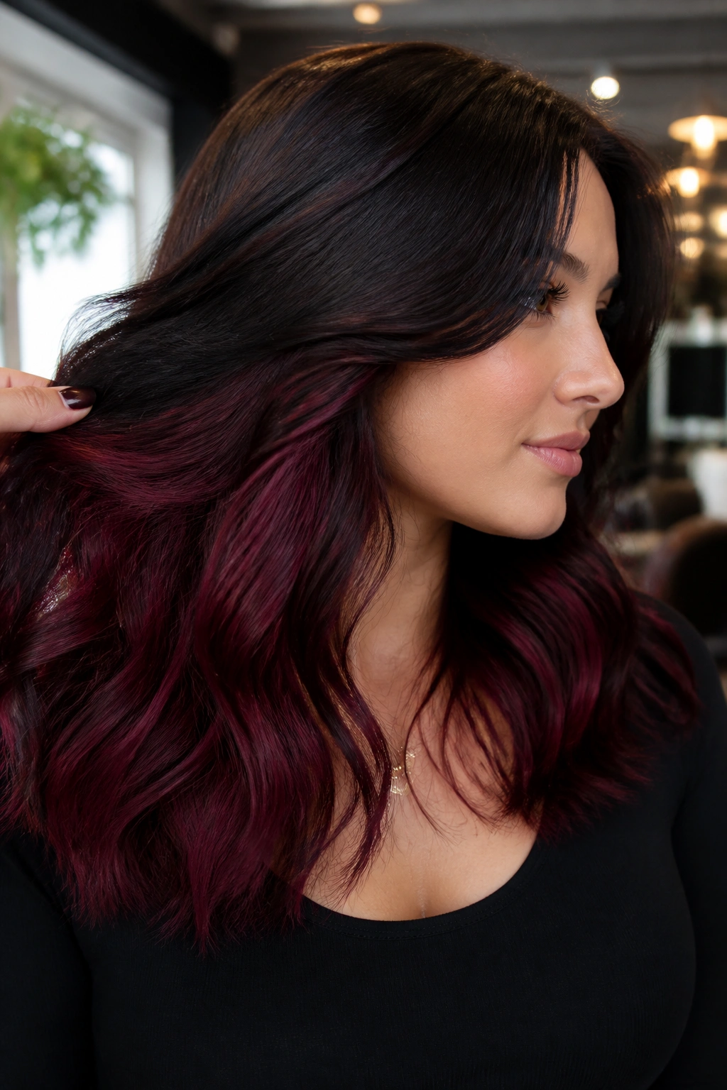 Close-up of a real woman showing burgundy underlights peeking from a dark top layer