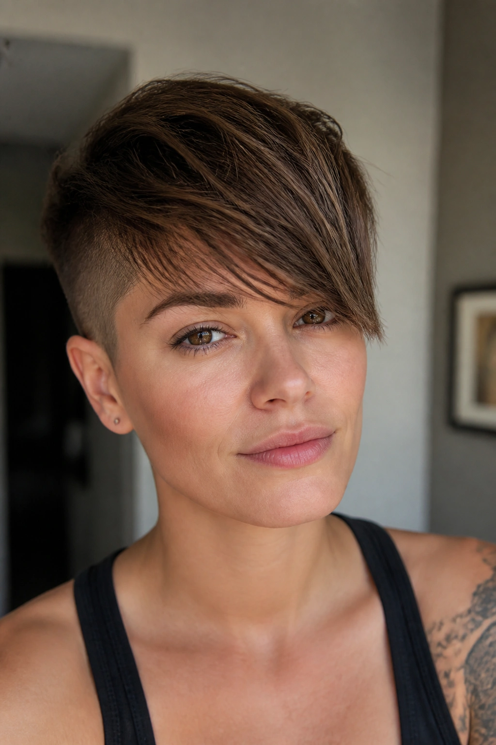 Close-up portrait of a woman with buzzed pixie and long fringe.
