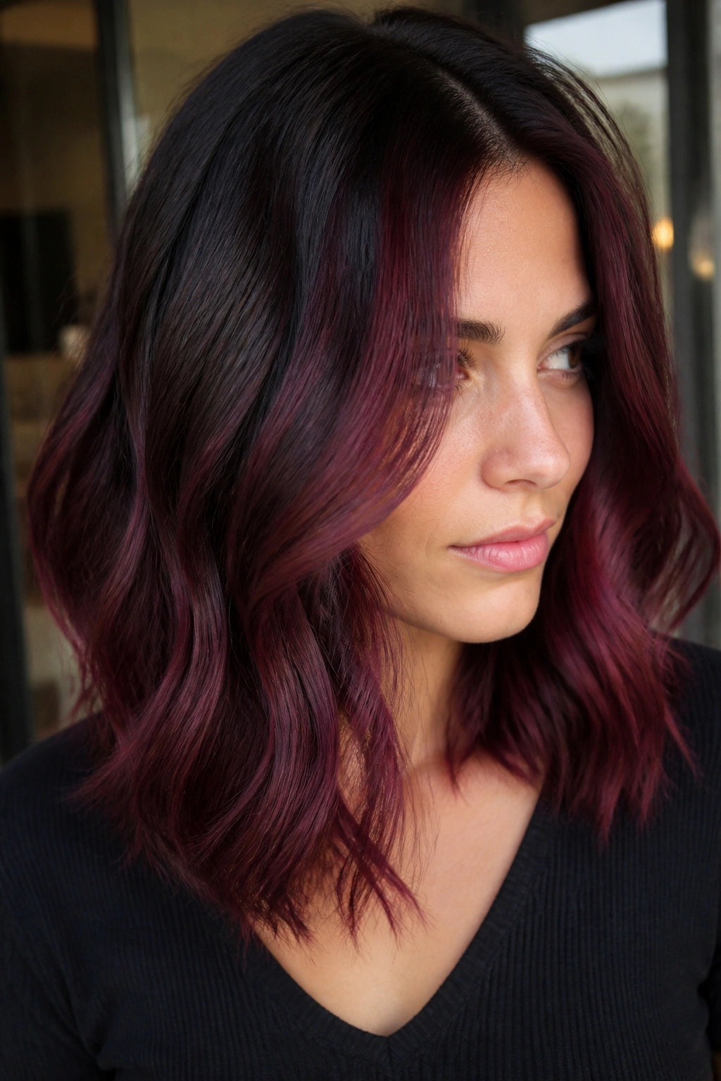 Close-up portrait of a real person with cabernet balayage on dark brown hair, wine-red panels framing the face.