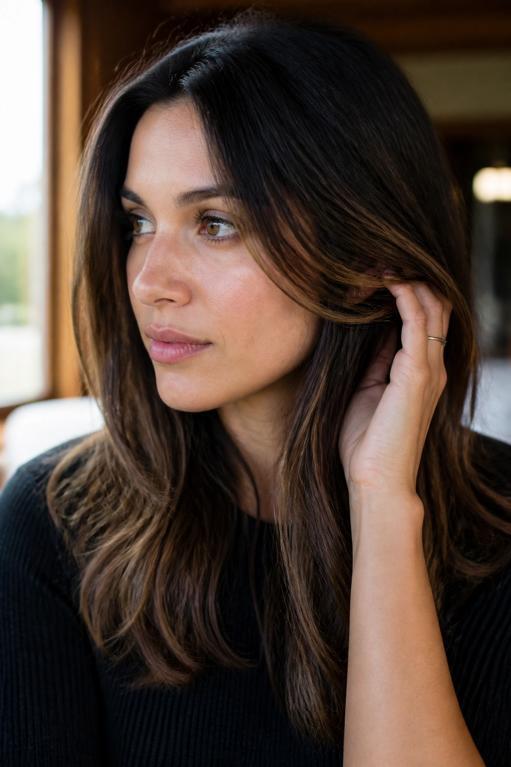 Close-up of a dark brunette with a subtle caramel veil balayage in natural window light