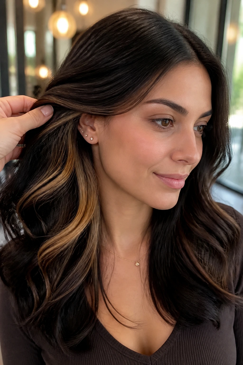 Close-up portrait of a woman with deep cocoa hair and caramel peekaboo panels.