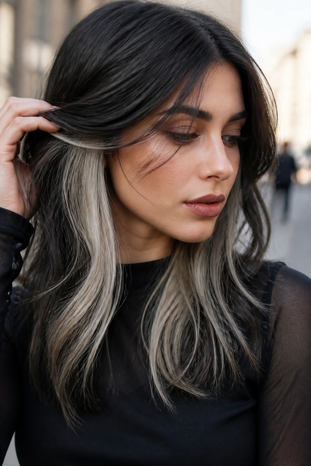 Portrait of a woman with charcoal brunette and peekaboo icy blonde panels.