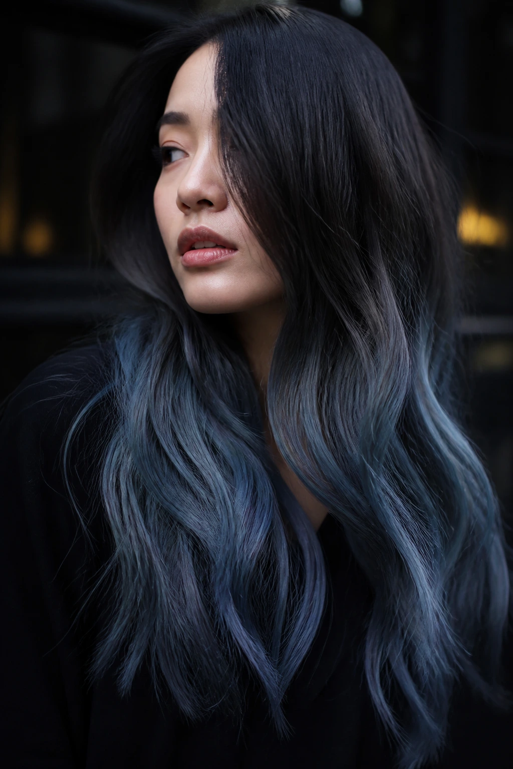 Portrait of a woman with charcoal-to-storm-blue gradient hair in moody lighting