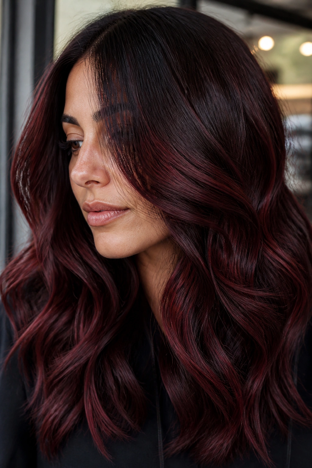 Close-up portrait of brunette with cherry cola balayage showing red-black reflect