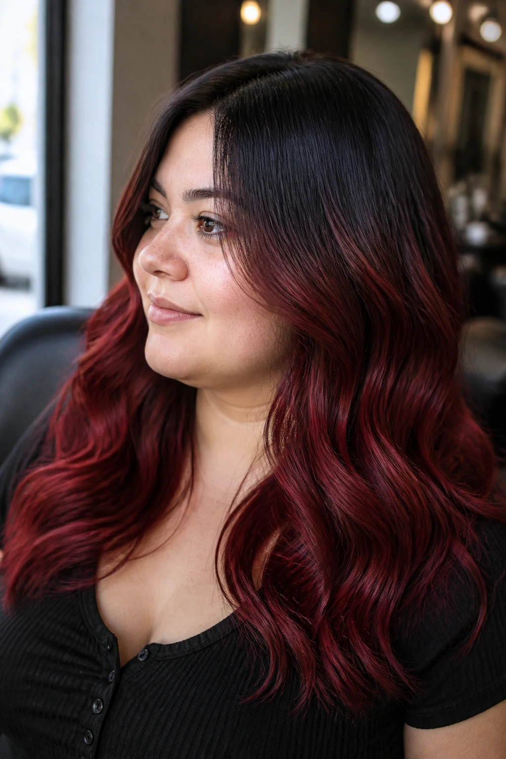Close-up portrait of a woman with a cherry cola gradient from black roots to red ends.