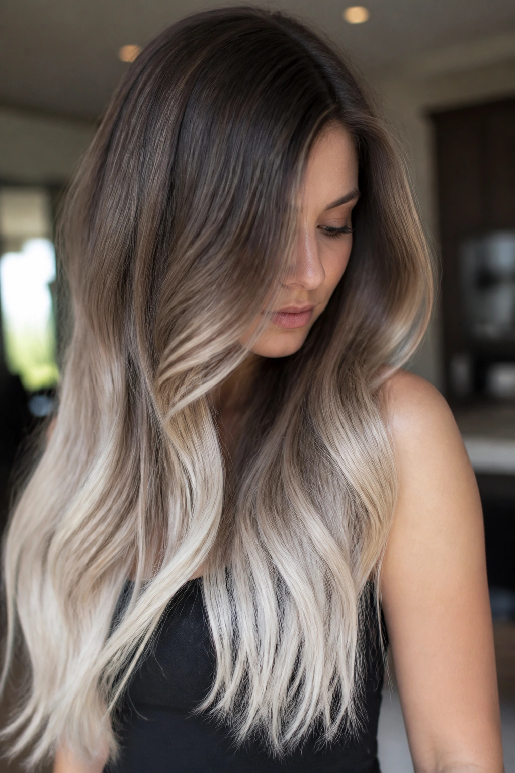 Close-up of a real person with chestnut roots fading to platinum-dipped ends in long hair.