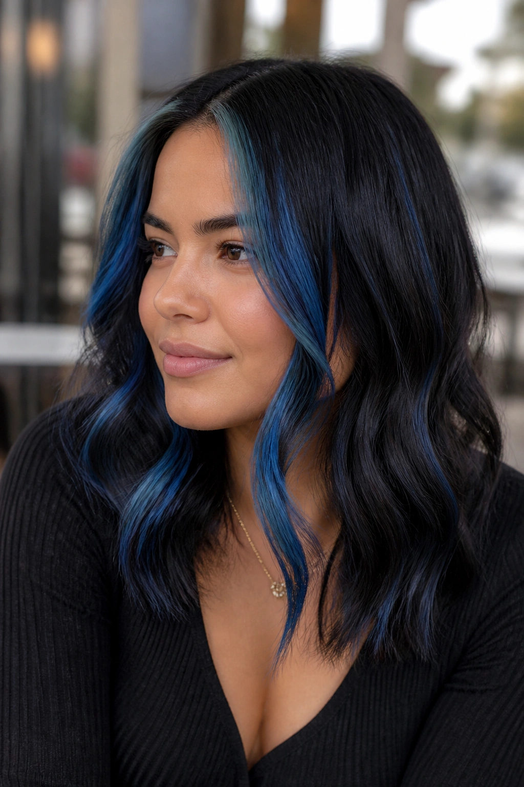 Close-up portrait of a real woman with bold blue-black chunky front streaks in hair