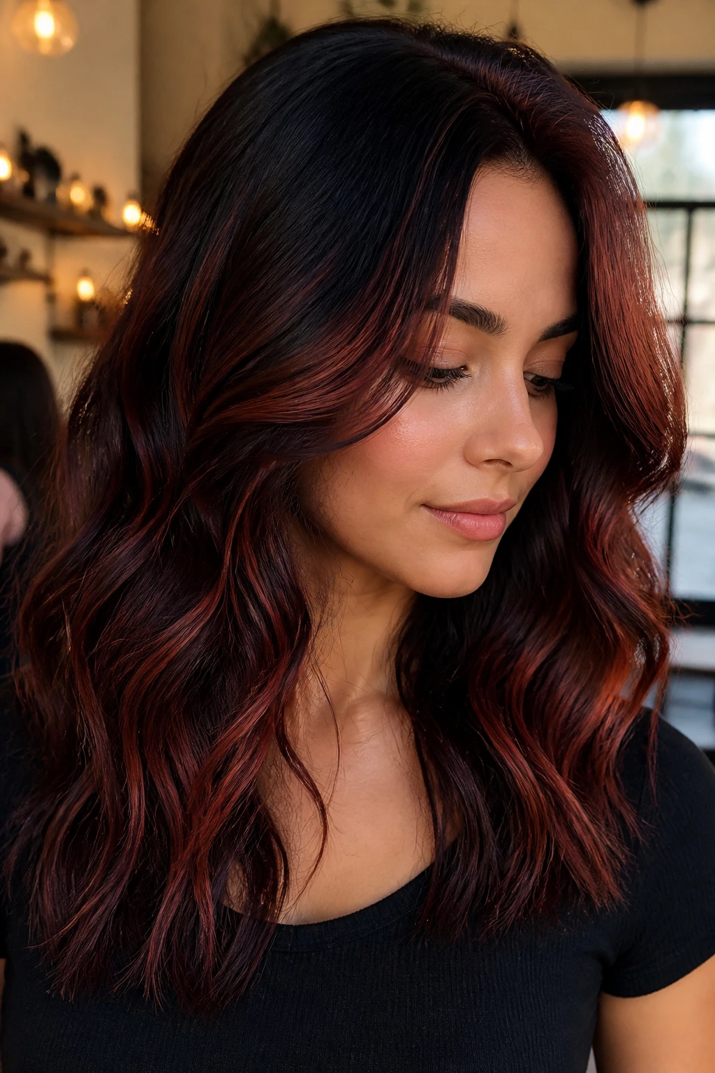Close-up portrait of a real person with cinnamon red waves on black hair in a warm indoor setting.
