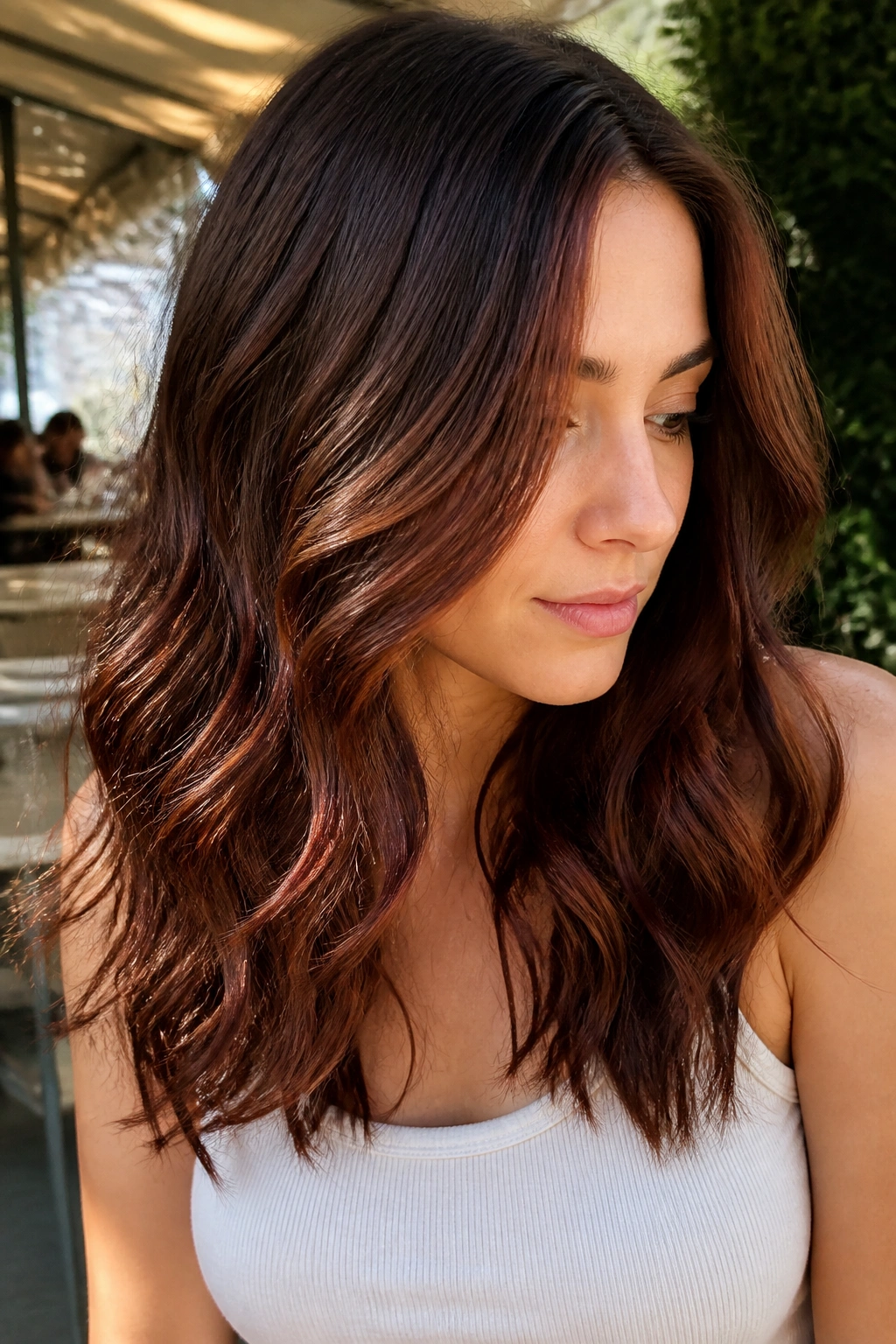 Close-up portrait of a real woman with Cocoa Ribbon Balayage hair catching light