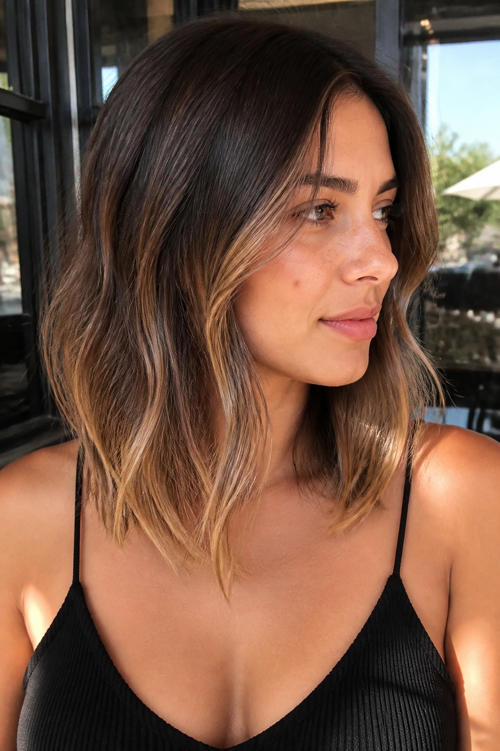 Portrait of a real woman with collarbone-length hair showing downward hazelnut balayage melt toward the collarbone.