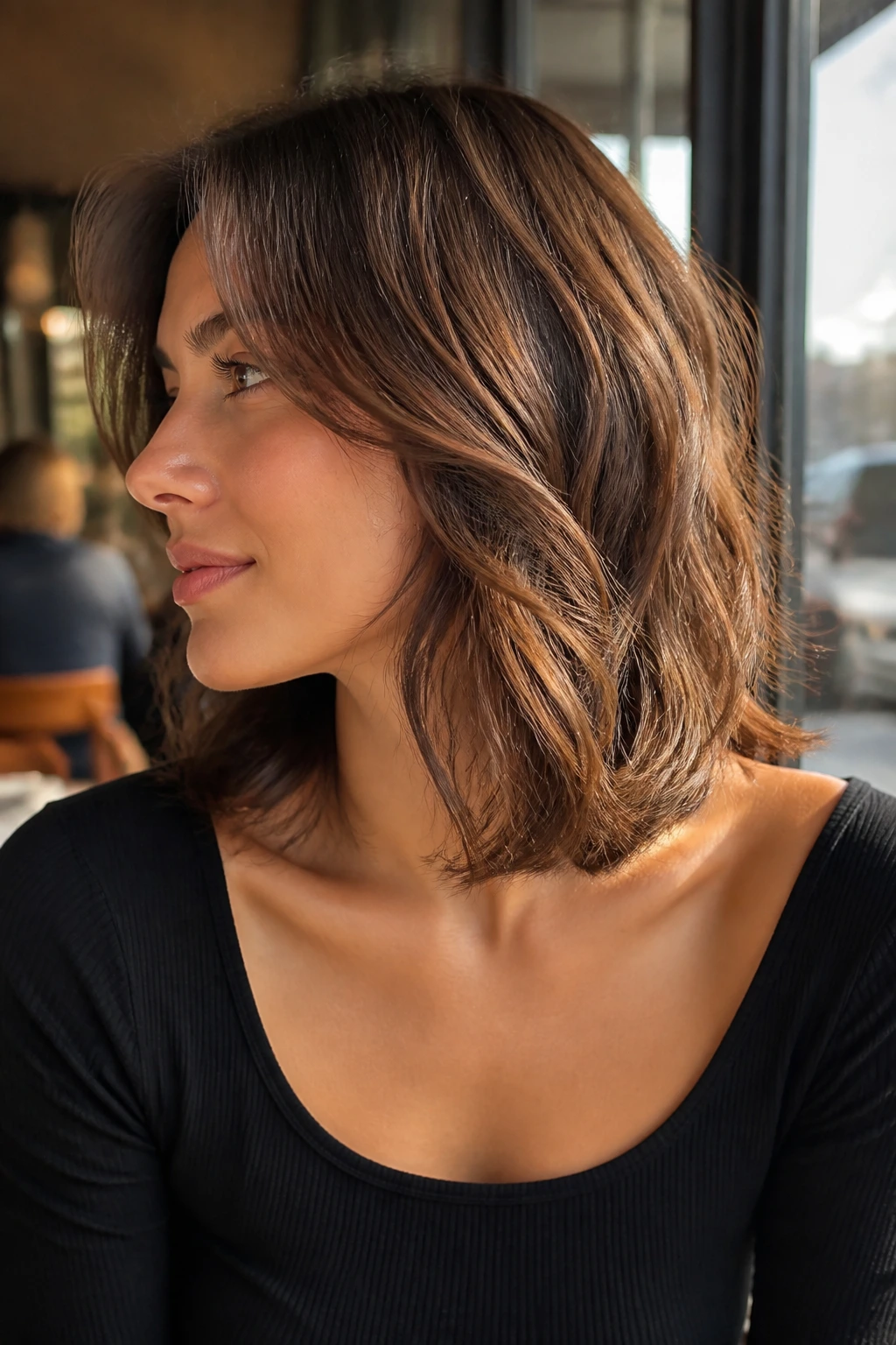 Profile view of woman with collarbone-skimming layers in long wavy hair