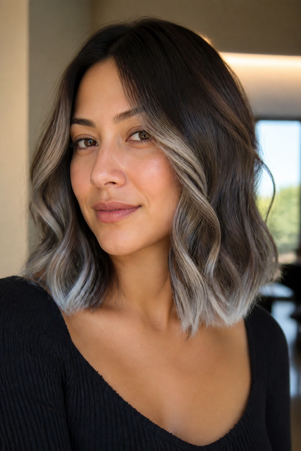 Close-up portrait of a real woman with a wavy collarbone-length cut and silver tipped ends.