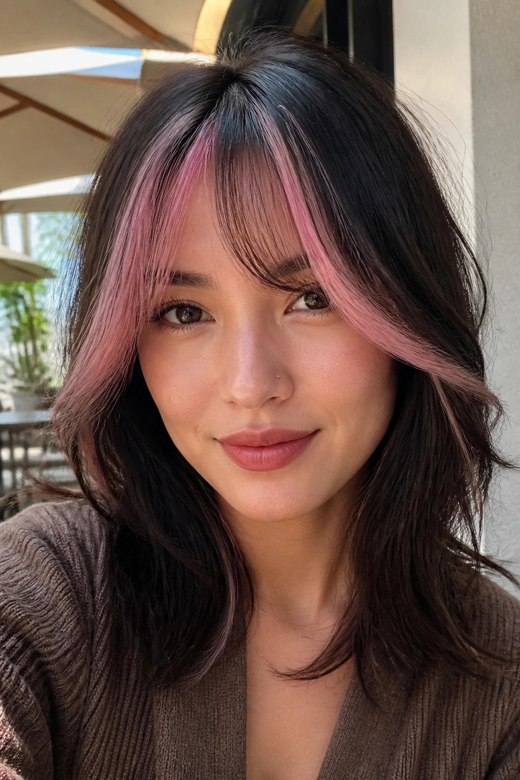 Close-up of a woman with cotton candy pink face-framing streaks on curtain bangs.