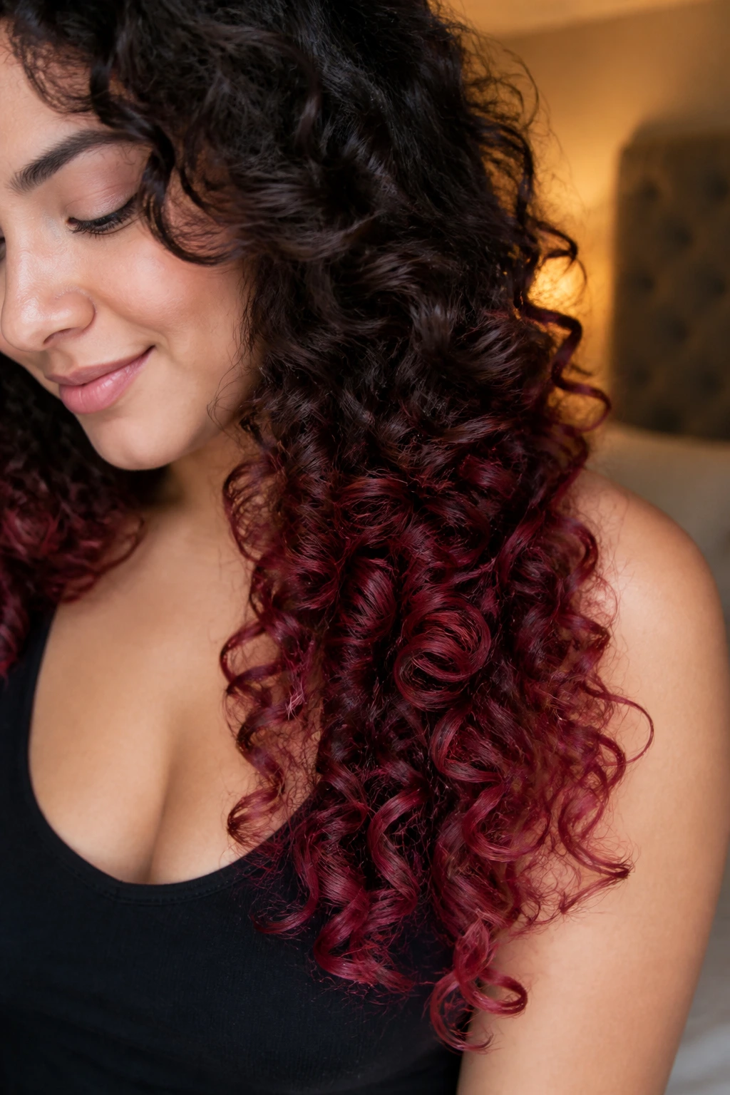 Curly hair with cranberry burgundy spiral ends in a cozy warm setting