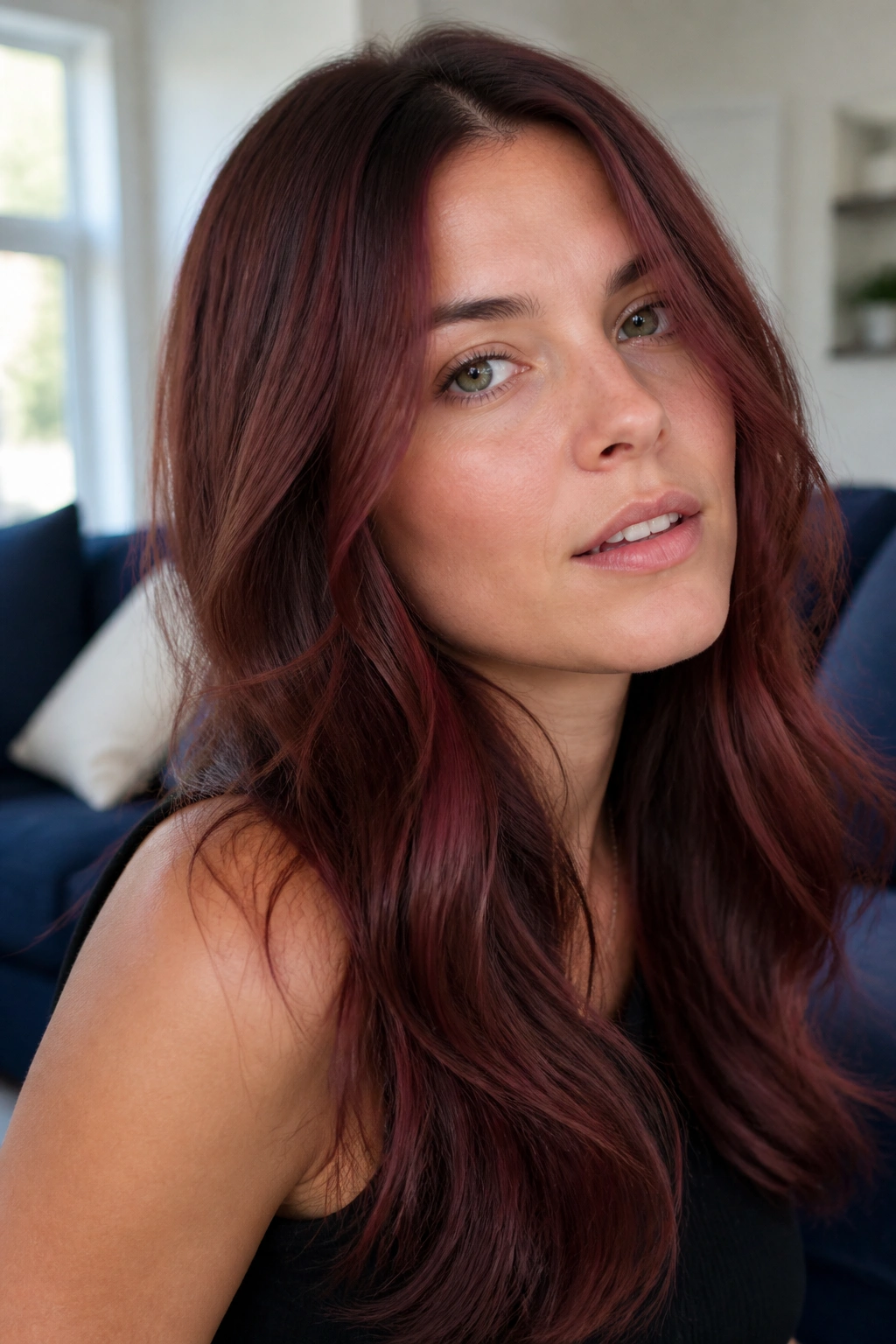 Close-up of a woman with cranberry chestnut hair in a bright living room