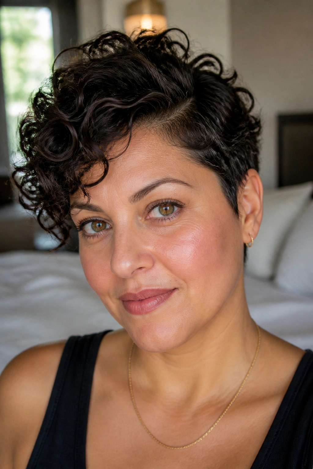 Close-up of a real woman with a side-parted curly pixie and crown lift, window light