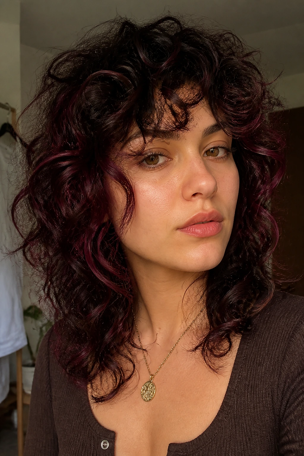 Close-up portrait of a real woman with a curly shag and burgundy ribbons woven through the curls