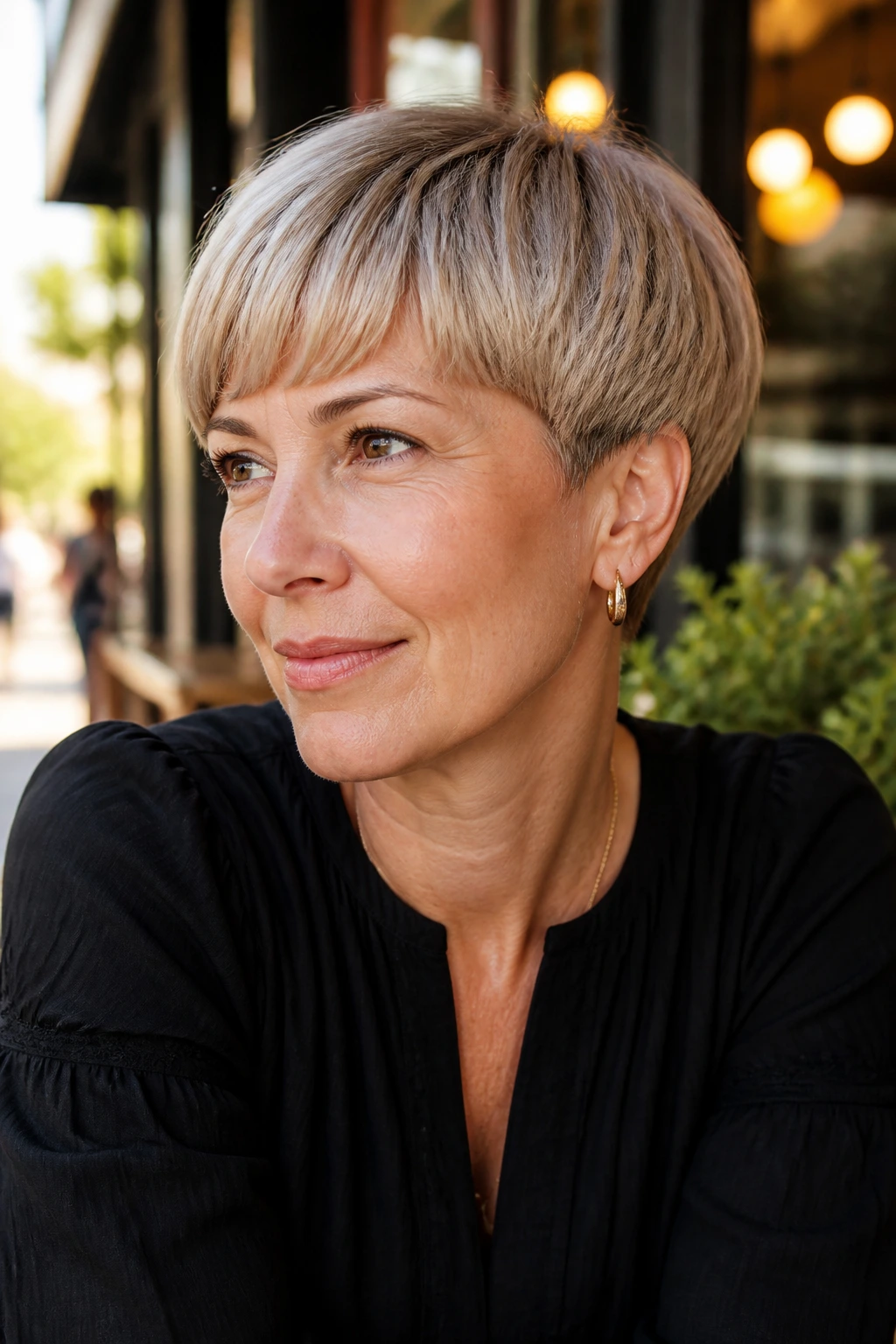 Close-up portrait of a real woman with Curved Bowl Pixie hairstyle in a cafe setting