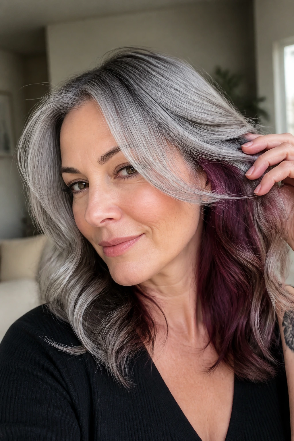 Close-up of deep plum underlayer visible beneath silver-grey hair on a real person
